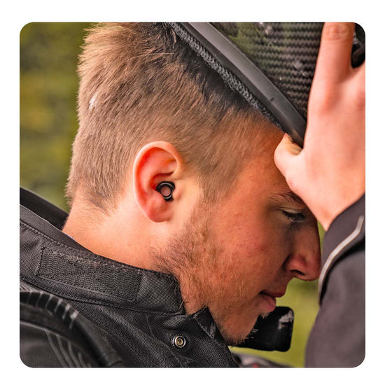 Image of a man putting on his motorcycle helmet, wearing Loop Experience earplugs.