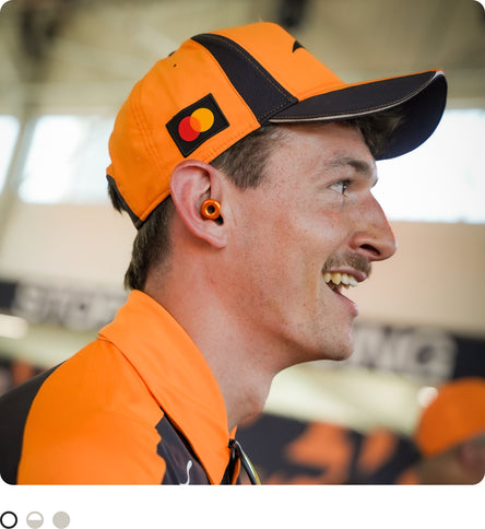Man wearing black and orange McLaren merchandise wearing McLaren x Loop Switch earplugs