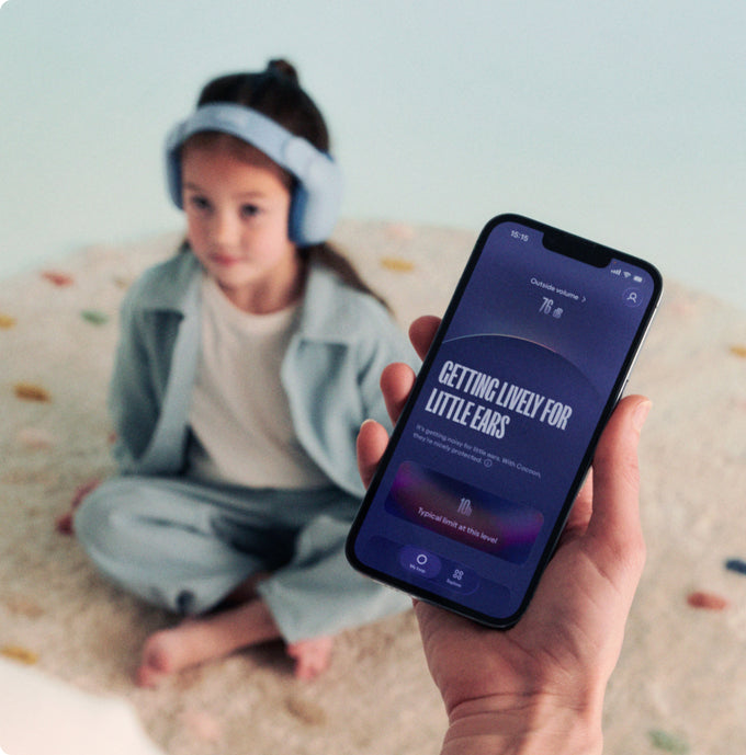 Child wearing headphones with a phone displaying an app interface on a light background
