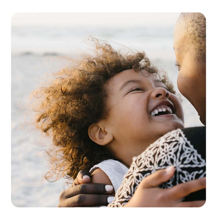Image of a toddler being held by her parent on the beach.