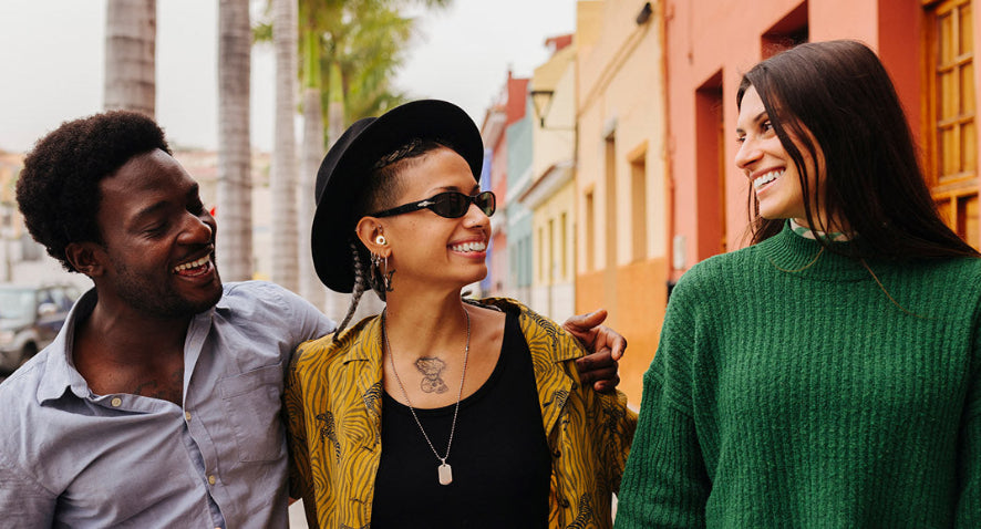 Three people walking together on a street with colorful buildings in the background